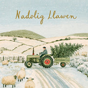 Nadolig Llawen — Tractor / Welsh card featuring a green tractor carrying a Christmas tree through the snow