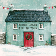 Nadolig Llawen i Chi Fel Teulu — Bwthyn glas / Welsh card featuring a blue cottage with a red door and wreath in the snow