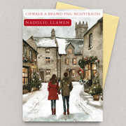 Cerdyn Nadolig ar gyfer Chwaer a Brawd yng Nghyfraith gyda cwpl yn cerdded drwy bentref eira, yn gorwedd yn fflat gydag amlen felen / Welsh Christmas card for a sister and brother-in-law, lying flat with an envelope