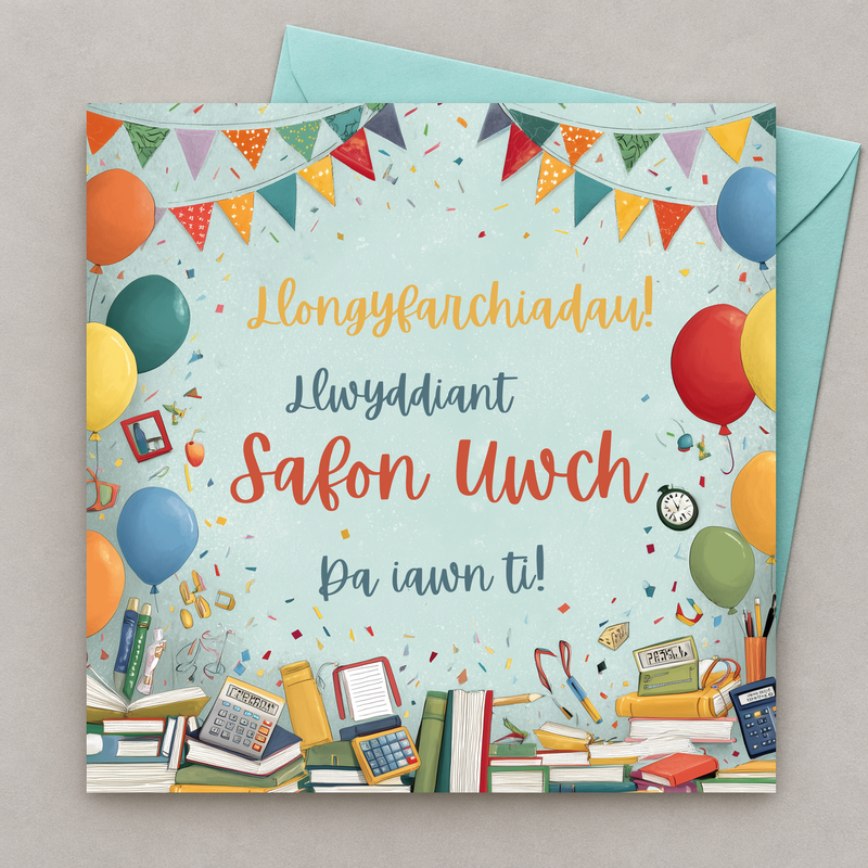 Cerdyn llwyddiant Safon Uwch gyda baneri, balwnau a llyfrau lliwgar, yn gorwedd yn fflat gydag amlen laswyrdd