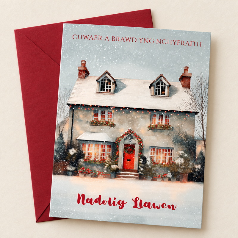 Cerdyn Nadolig Chwaer a Brawd yng Nghyfraith / Welsh Christmas card with a cottage with a red door in the snow, lying flat beside a deep red envelope.