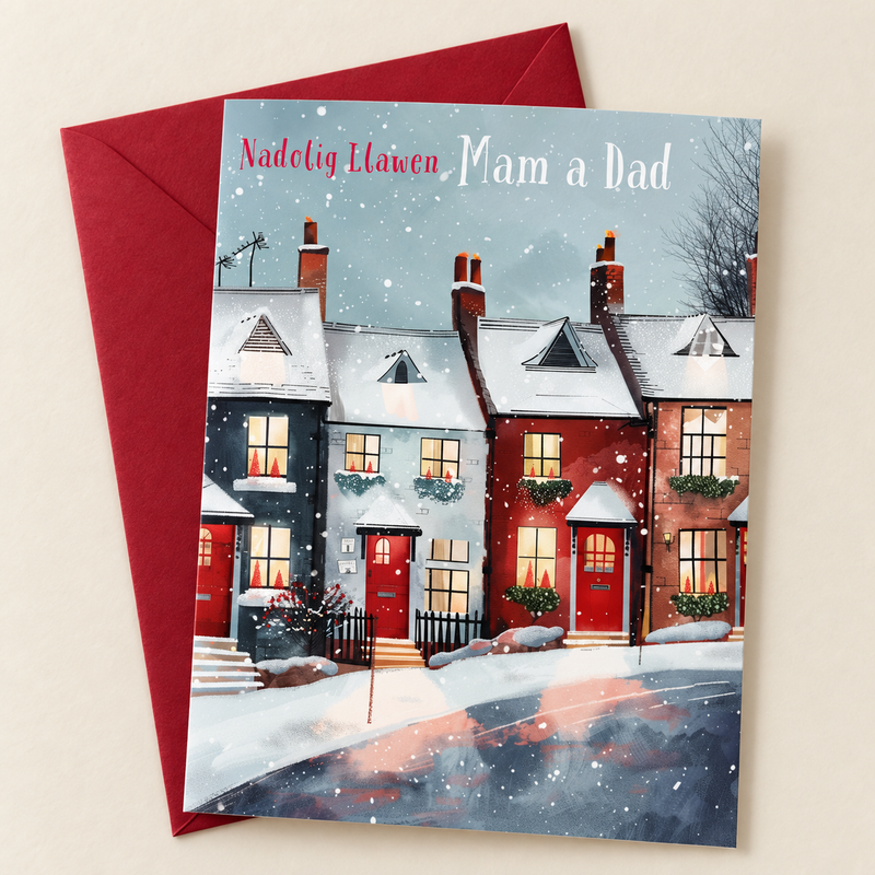 Cerdyn Nadolig Mam a Dad – Tai yn yr Eira / Welsh Christmas card with a row of houses in the snow, lying flat beside a deep red envelope.