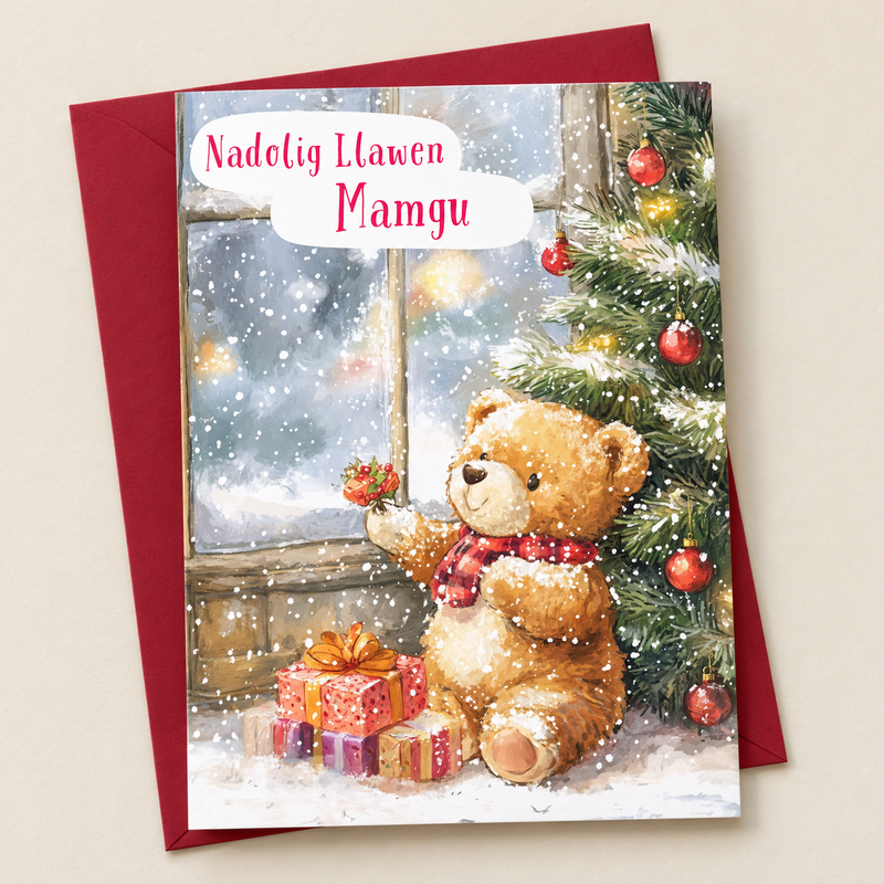 Cerdyn Nadolig Mamgu – Tedi a Choeden / Welsh Christmas card with a teddy beside a Christmas tree, lying flat beside a deep red envelope.