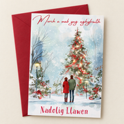 Cerdyn Nadolig Merch a Mab yng Nghyfraith – Coeden / Welsh Christmas card with two people beside a Christmas tree, lying flat beside a deep red envelope.