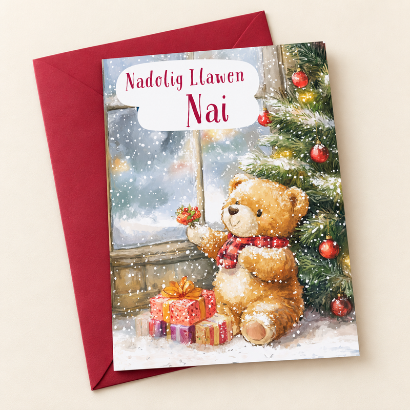 Cerdyn Nadolig Nai – Tedi a Choeden / Welsh Christmas card with a teddy beside a Christmas tree, lying flat beside a deep red envelope.