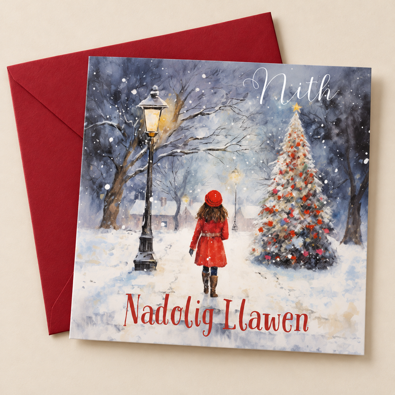 Cerdyn Nadolig Nith – Coeden Nadolig / Welsh Christmas card with a girl in a red coat beside a Christmas tree, lying flat beside a deep red envelope.