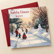 Cerdyn Nadolig Wyrion – Eira / Welsh Christmas card with children playing in the snow, lying flat beside a deep red envelope.